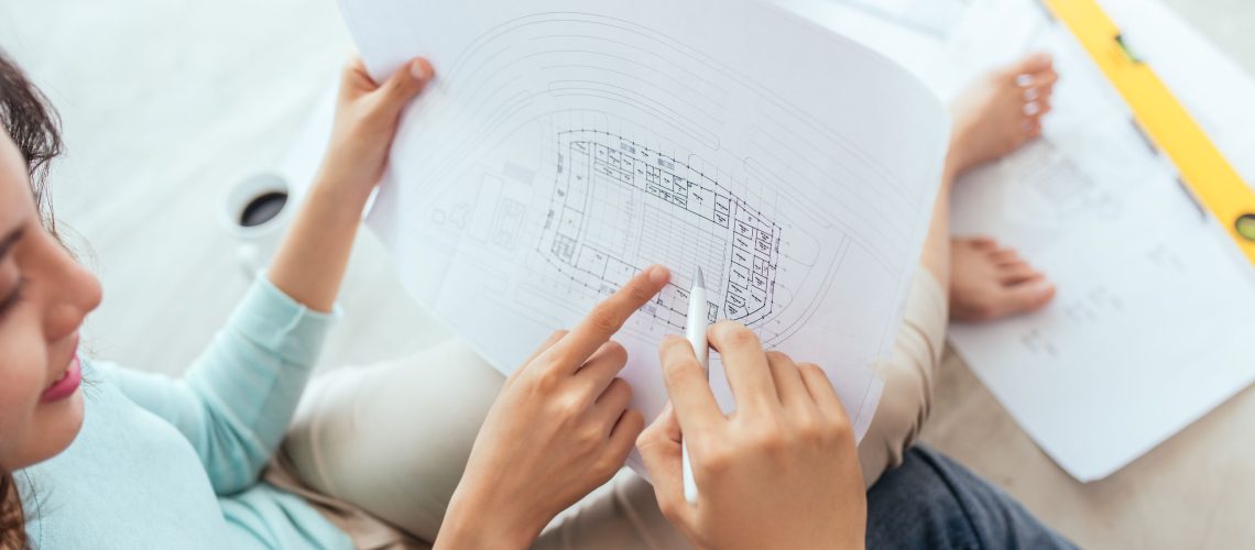 Cheerful asian couple looking at construction house plan